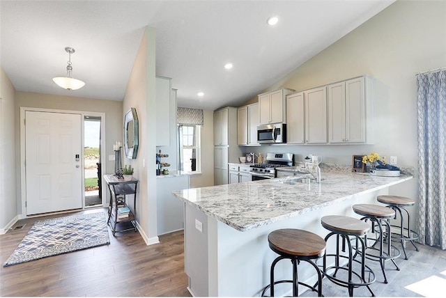 kitchen with kitchen peninsula, hanging light fixtures, vaulted ceiling, and appliances with stainless steel finishes