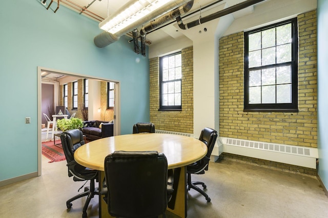 dining area featuring brick wall and baseboards