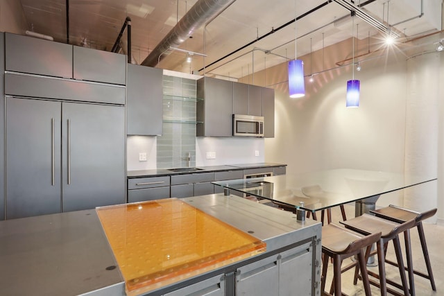 kitchen with gray cabinets, stainless steel microwave, dark countertops, and a sink