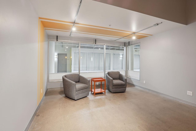 living area featuring concrete floors and baseboards