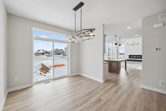 unfurnished dining area with a wealth of natural light, a textured ceiling, and light wood-type flooring