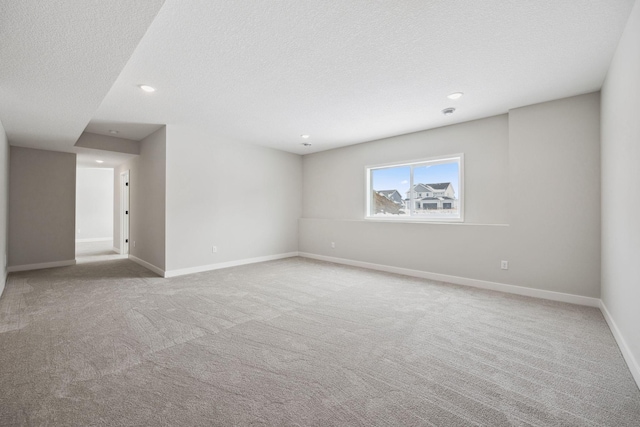 spare room featuring light colored carpet and a textured ceiling