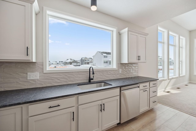 kitchen with a healthy amount of sunlight, dishwasher, sink, and white cabinets