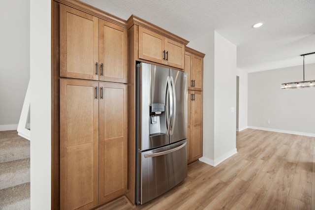 kitchen with pendant lighting, light hardwood / wood-style flooring, a textured ceiling, and stainless steel refrigerator with ice dispenser