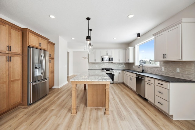 kitchen featuring white cabinetry, dark stone countertops, a kitchen island, pendant lighting, and stainless steel appliances