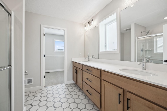 bathroom with vanity, an enclosed shower, and a textured ceiling