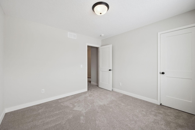 unfurnished bedroom featuring light colored carpet and a textured ceiling