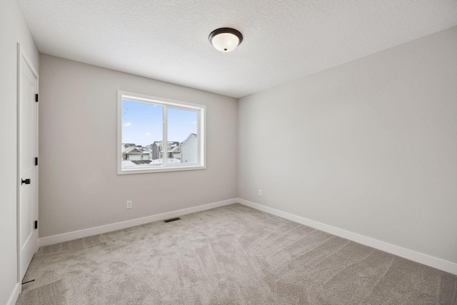 empty room with light carpet and a textured ceiling