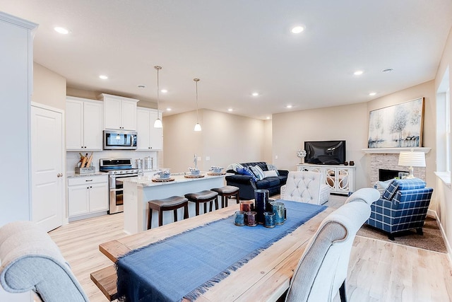 dining area featuring a stone fireplace and light hardwood / wood-style floors