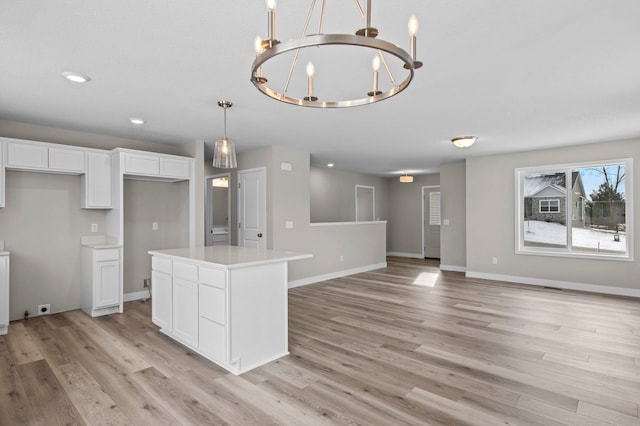 kitchen featuring white cabinetry, decorative light fixtures, a kitchen island, and light wood-type flooring