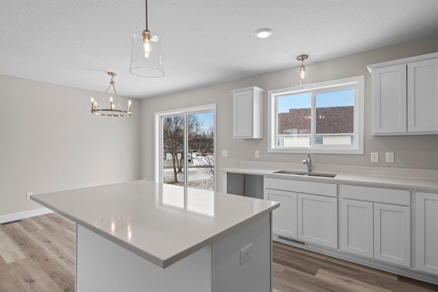 kitchen with sink, white cabinetry, hanging light fixtures, plenty of natural light, and a kitchen island