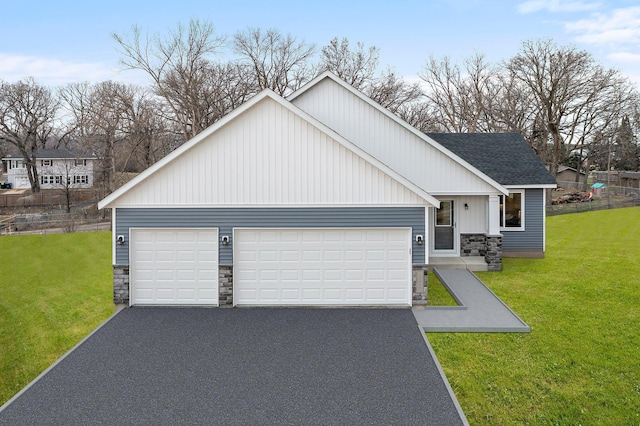 view of front facade with aphalt driveway, a shingled roof, stone siding, a front yard, and a garage