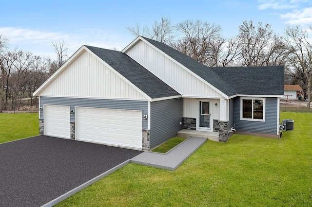 view of front of house with a front lawn, driveway, stone siding, a garage, and a shingled roof