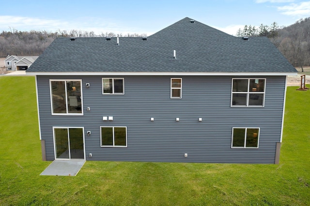 back of house with a yard, a patio, and a shingled roof