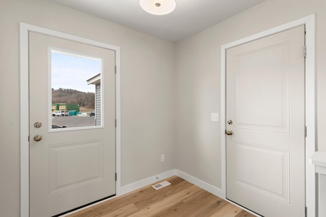 entryway with baseboards, visible vents, and light wood-type flooring