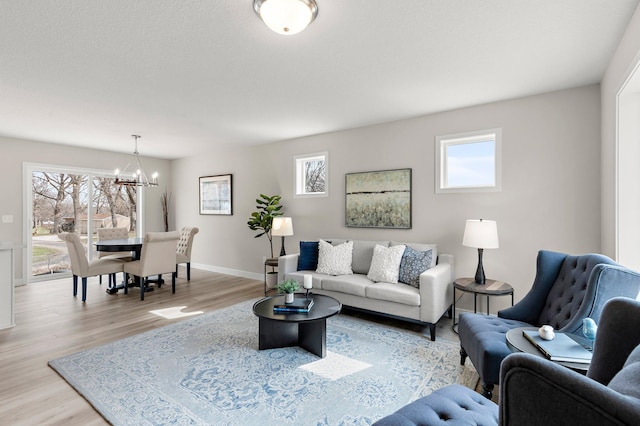 living room featuring an inviting chandelier, light wood-style floors, and baseboards