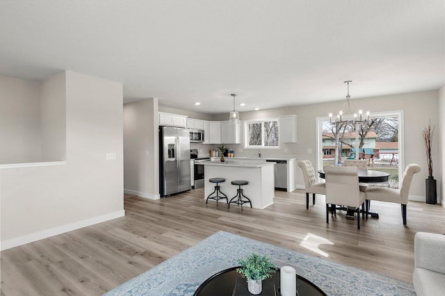 living area featuring baseboards, a notable chandelier, light wood finished floors, and recessed lighting