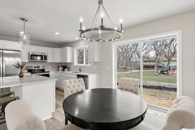 dining space with a wealth of natural light, an inviting chandelier, light wood finished floors, and recessed lighting