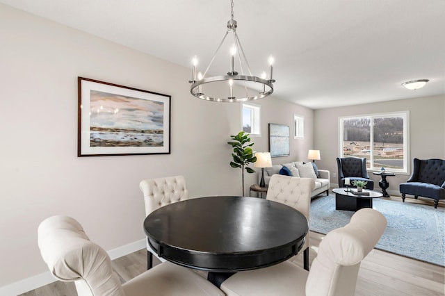 dining room with baseboards, an inviting chandelier, a healthy amount of sunlight, and light wood-type flooring