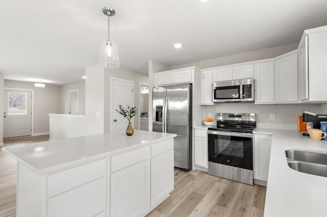 kitchen featuring stainless steel appliances, light wood finished floors, light countertops, white cabinetry, and a kitchen island
