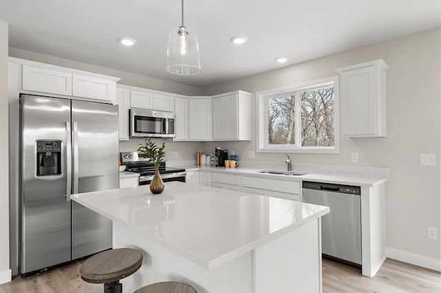 kitchen featuring white cabinets, stainless steel appliances, light wood finished floors, and a sink