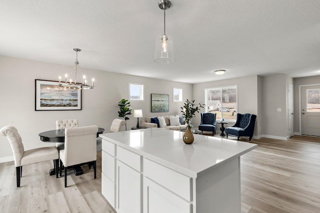 kitchen with baseboards, a wealth of natural light, a kitchen island, and light wood-type flooring