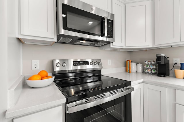 kitchen featuring light stone countertops, stainless steel appliances, and white cabinetry