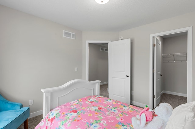 bedroom with a spacious closet, visible vents, and carpet flooring