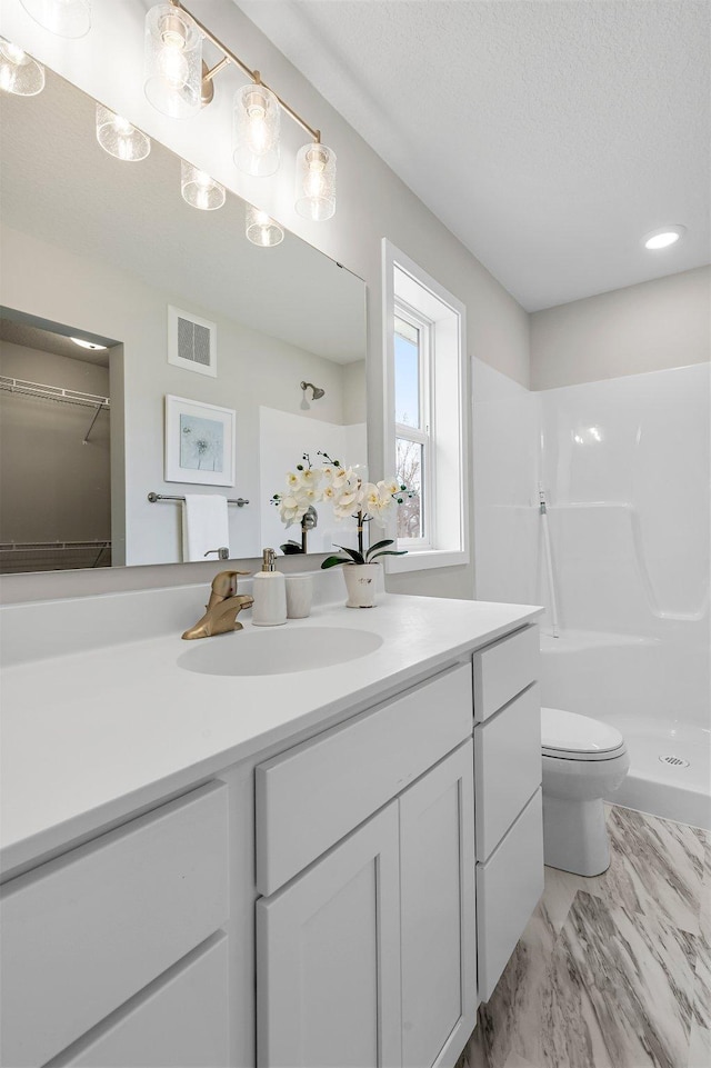 bathroom featuring marble finish floor, visible vents, toilet, vanity, and a stall shower