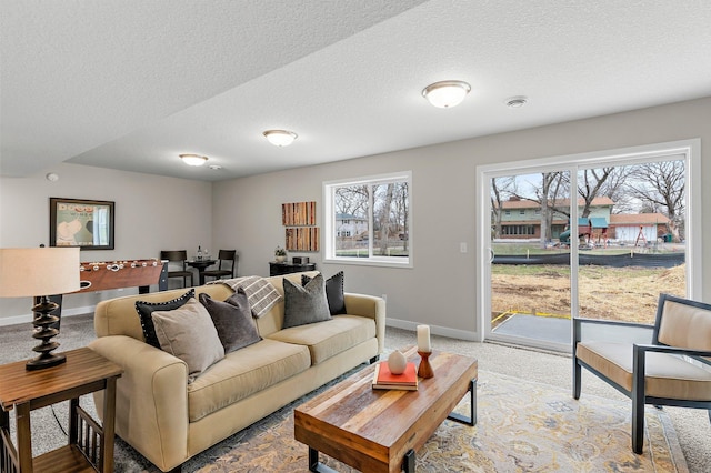 living area featuring baseboards, a textured ceiling, and a healthy amount of sunlight