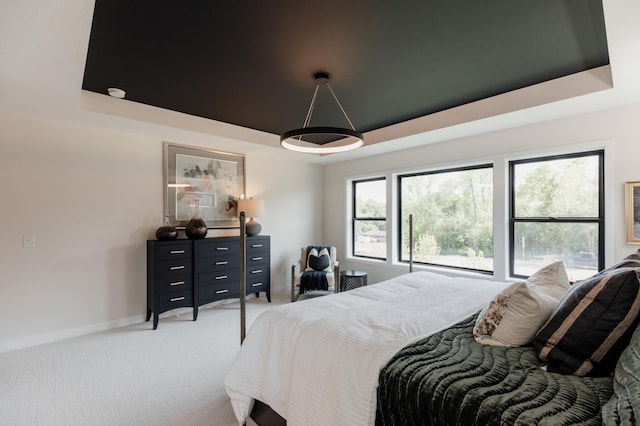 bedroom featuring light carpet and a tray ceiling