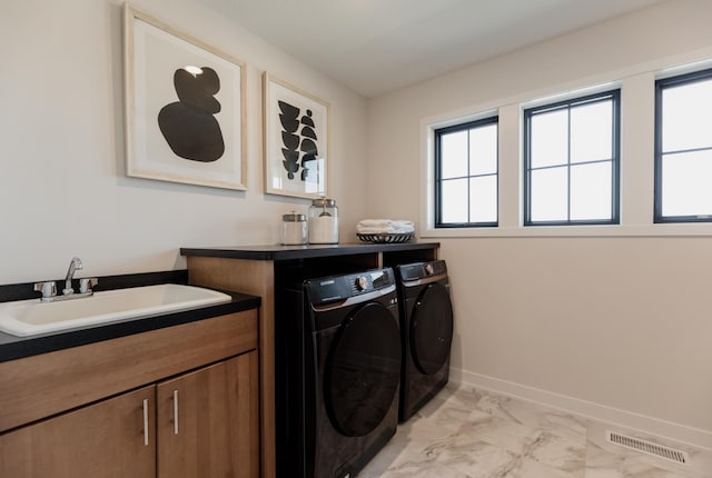 laundry room featuring washing machine and clothes dryer, sink, and cabinets