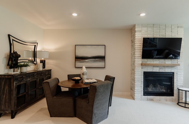 carpeted dining area with a brick fireplace