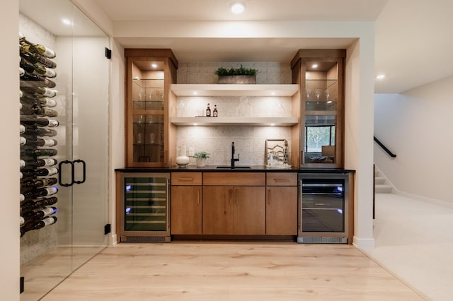 bar with light hardwood / wood-style flooring, beverage cooler, and sink