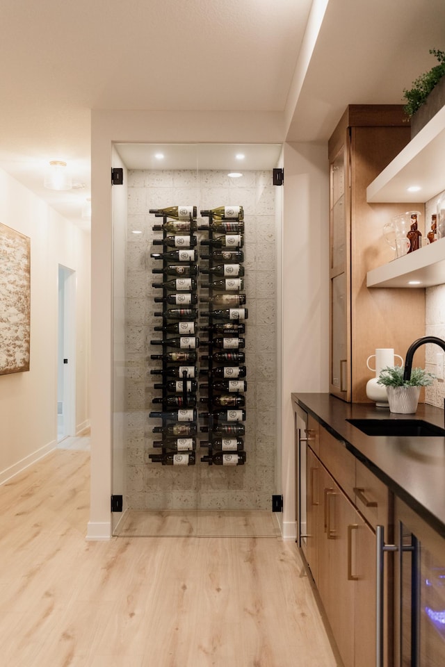 wine area with electric panel, light hardwood / wood-style flooring, and sink