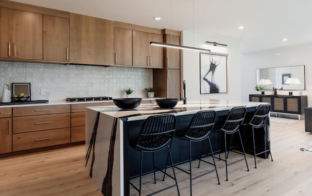 kitchen featuring stainless steel gas stovetop, a breakfast bar, a kitchen island, and light hardwood / wood-style flooring