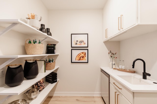 clothes washing area with sink and light hardwood / wood-style floors