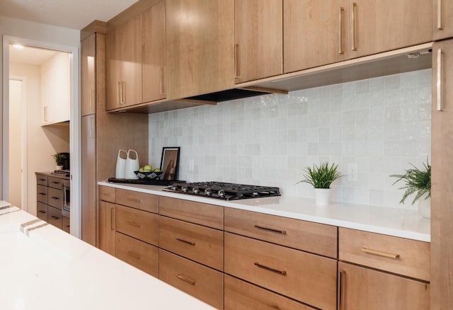 kitchen with decorative backsplash, light brown cabinets, and stainless steel gas stovetop