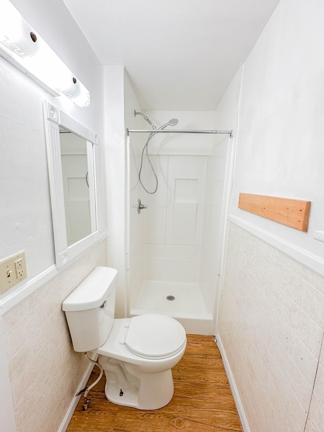 bathroom featuring a shower, wood-type flooring, toilet, and tile walls