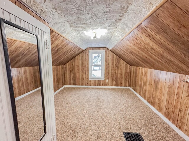 bonus room featuring carpet flooring, wooden walls, and lofted ceiling