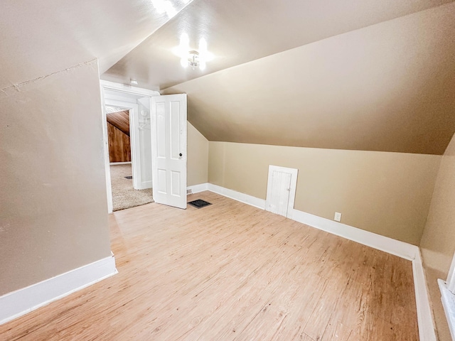 additional living space with light hardwood / wood-style floors and vaulted ceiling