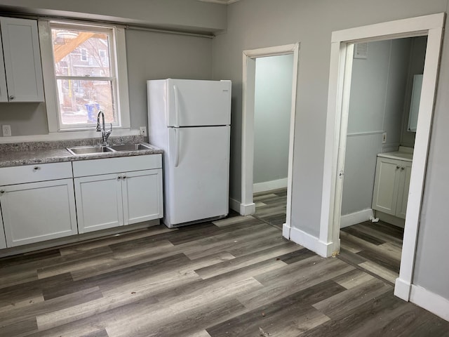 kitchen with white refrigerator, dark hardwood / wood-style flooring, white cabinetry, and sink