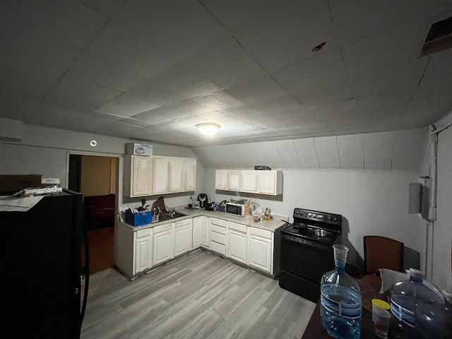 kitchen featuring light wood-type flooring, electric range, white cabinetry, and vaulted ceiling