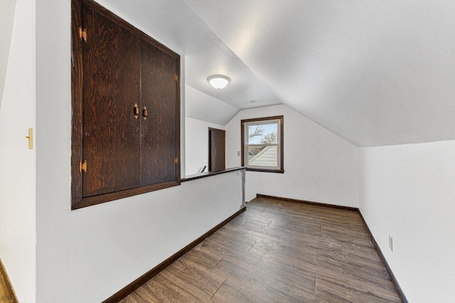 bonus room with dark hardwood / wood-style flooring and vaulted ceiling