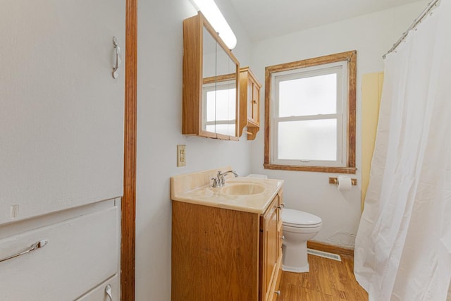 bathroom with a shower with shower curtain, hardwood / wood-style floors, vanity, and toilet