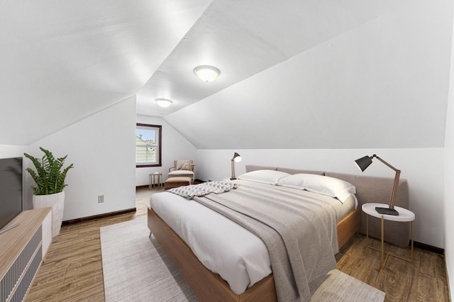 bedroom with hardwood / wood-style floors and vaulted ceiling