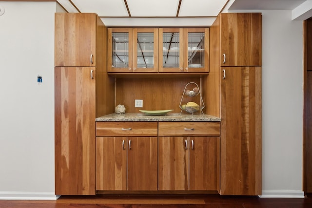 bar featuring light stone countertops and dark hardwood / wood-style flooring