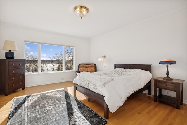 bedroom featuring crown molding and light hardwood / wood-style flooring