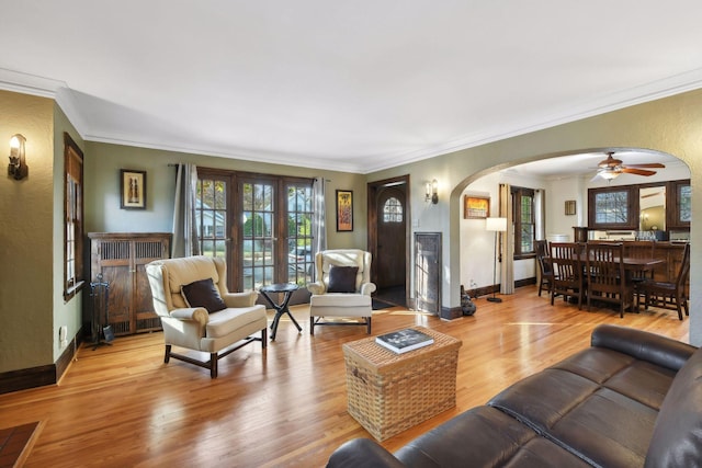 living room with crown molding, plenty of natural light, and light hardwood / wood-style flooring