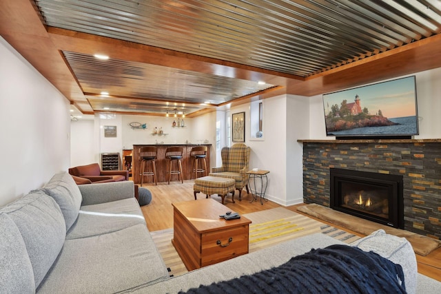 living room with bar, a fireplace, wood ceiling, and light hardwood / wood-style flooring